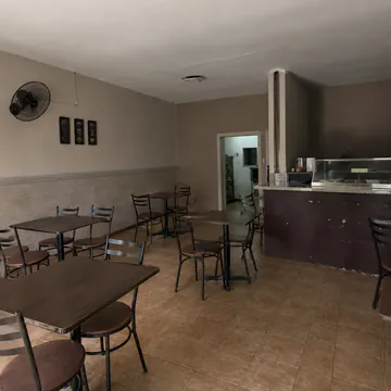 Interior con mesas y sillas vacías, sin decoración